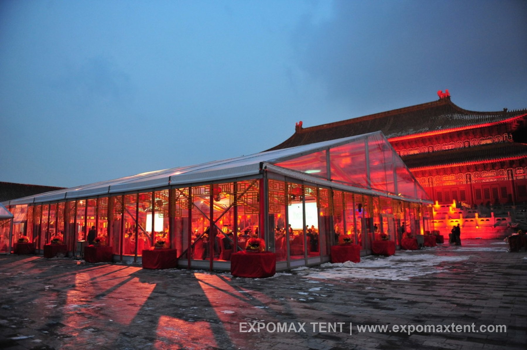 Transparent tent event beside a historical building at night